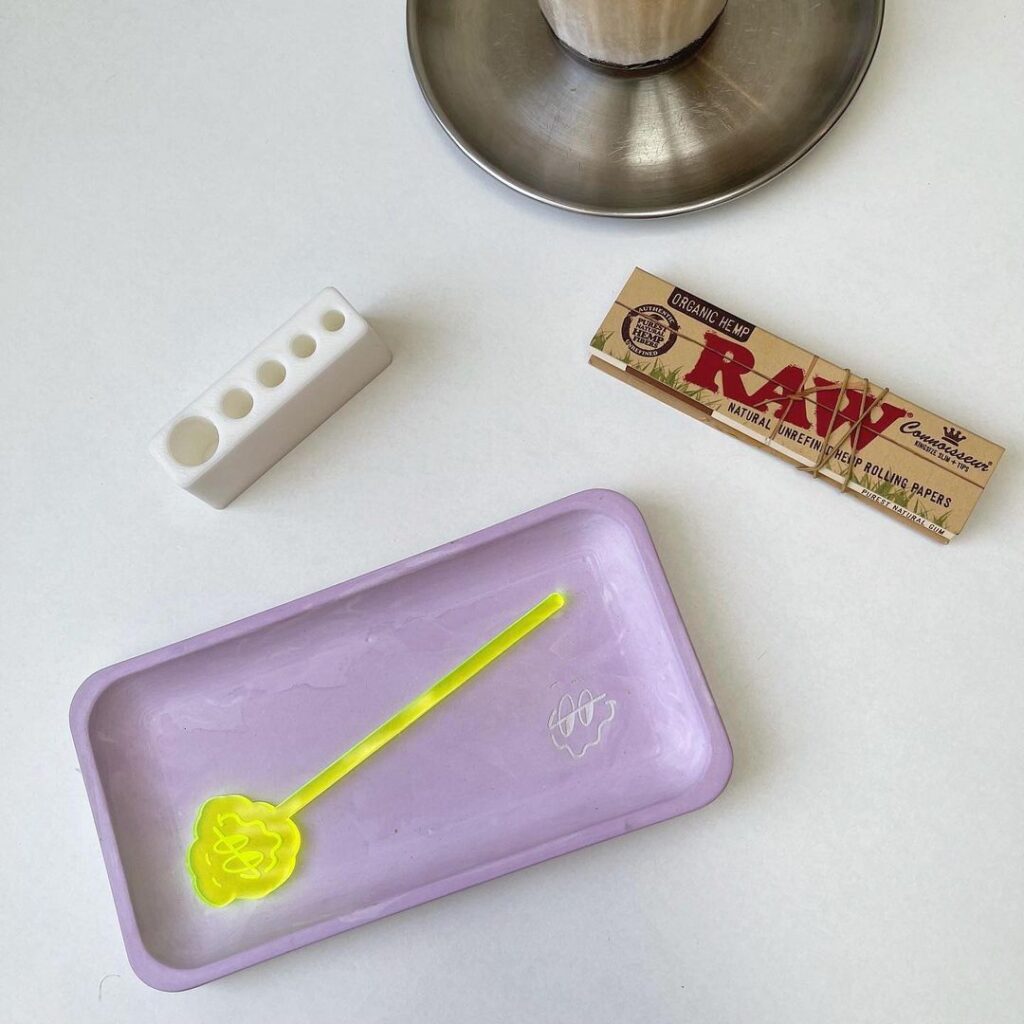 Rolling tray, tamping stick, joint holder, rolling papers on white table