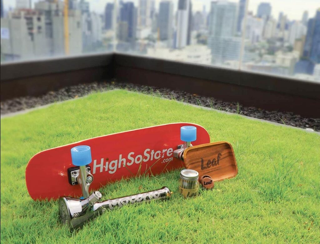 skateboard, bong, rolling tray and grinder on a grassy rooftop in Bangkok