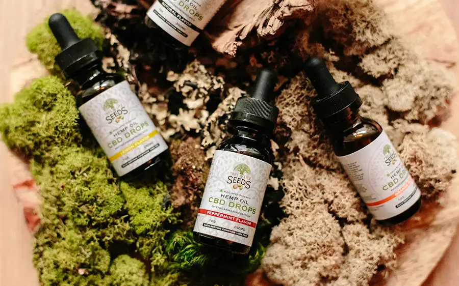 A selection of flavored hemp CBD oil bottles arranged on a natural display of moss and bark.
