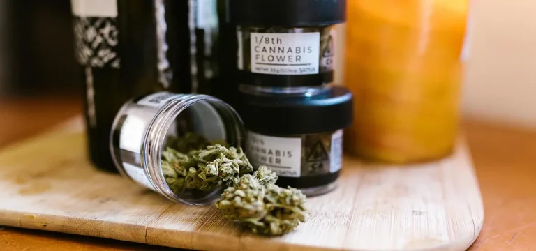 A jar of THC-rich cannabis flower labeled and opened on a wooden tray, representing legal cannabis in Thailand.